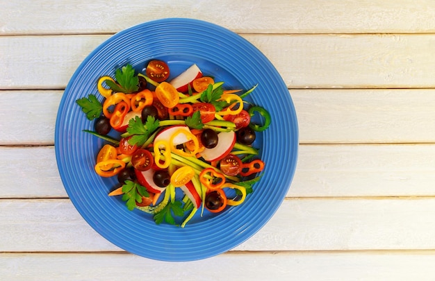 Summer salad with tomatoes in white plate on wood table