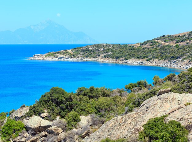 Summer sea scenery with aquamarine transparent water and Athos Mount. View from shore (Sithonia, Halkidiki, Greece).