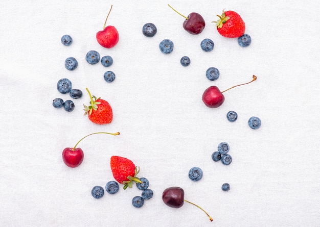 Summer set with berries: cherry, strawberry, blueberry or bilberry and blackberry on white surface