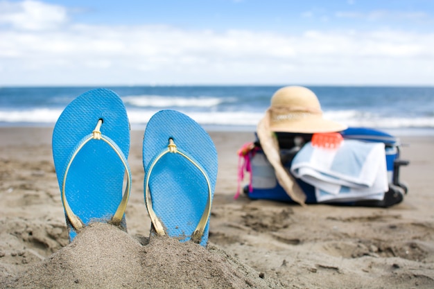 Summer shoes on the beach sand with travel suitcase