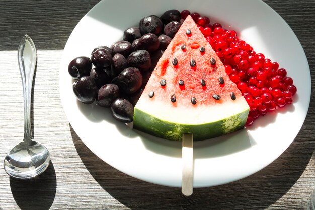 Summer snack Fresh berries and fruits on a wooden table with green leaves of plants