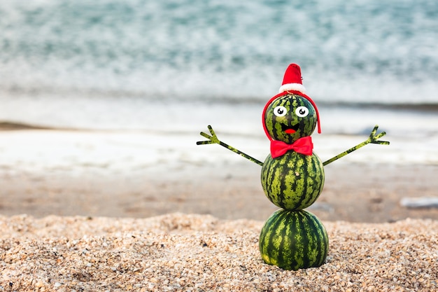 Summer snowman from watermelons in a red bow-tie and Santa's hat.