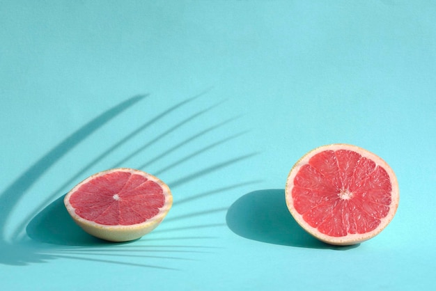 Summer still life with two cut grapefruits on blue background