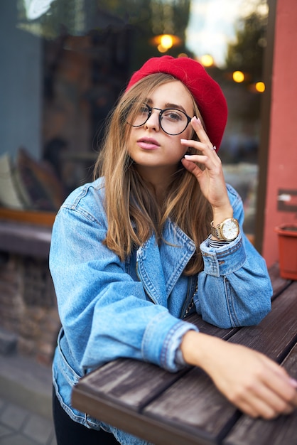 Summer sunny lifestyle fashion portrait of young stylish hipster woman walking on street,wearing cute trendy outfit with red hat