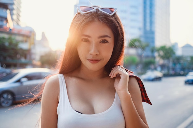 Summer sunny lifestyle portrait of young stylish hipster woman walking on the street wearing cute trendy outfit Young Asian women tourist traveler smiling in bangkok street fashion