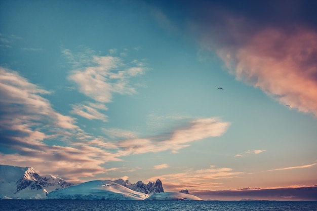 Summer sunset in Antarctica. Coloured Sunset Clouds over ocean with mountains in the background. Beautiful winter landscape