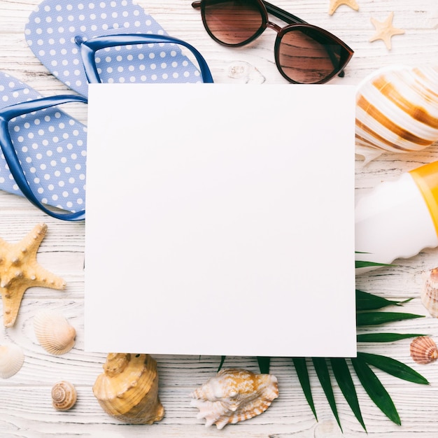 Summer time concept with blank greeting card and blank white paper on colored background Seashells from ocean shore in the shape of frame separated with space for text top view