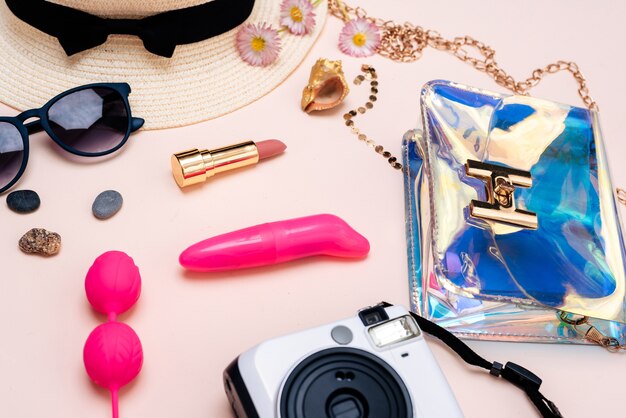 Summer travel accessories. women's set of adult toys, camera, hat, glasses on pink