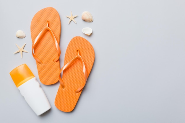 Summer travel concept Beach accessories Flip flops and starfish on white Top view on colored background