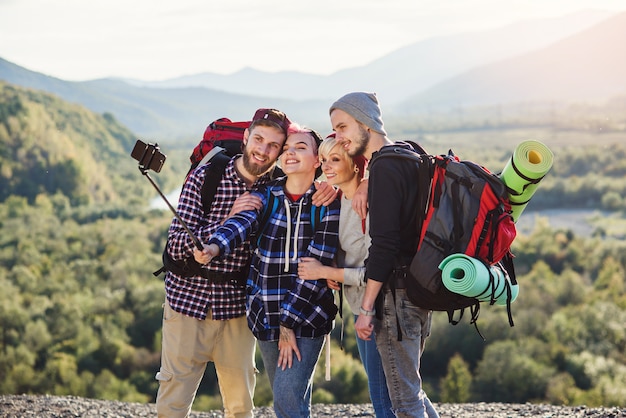 Summer travel concept. Happy friends using paper map near rented car in nature.