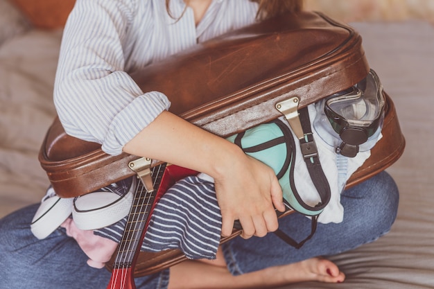 Summer travel and vacation . Young woman packing suitcase at home