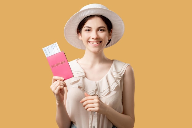 Summer trip Passport control Visa office Happy woman white hat holding foreign id and tickets looking at camera isolated on beige