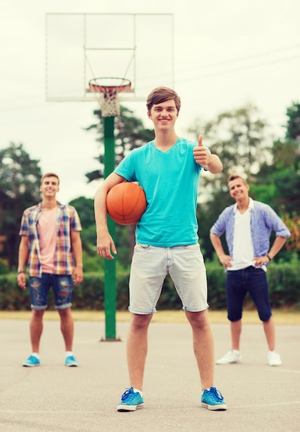 summer vacation, holidays, games, gesture and people concept - group of smiling teenagers playing basketball and showing thumbs up outdoors