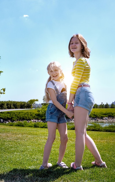 Summer and vacation,  Smiling happy girls sisters on the  meadow near the river