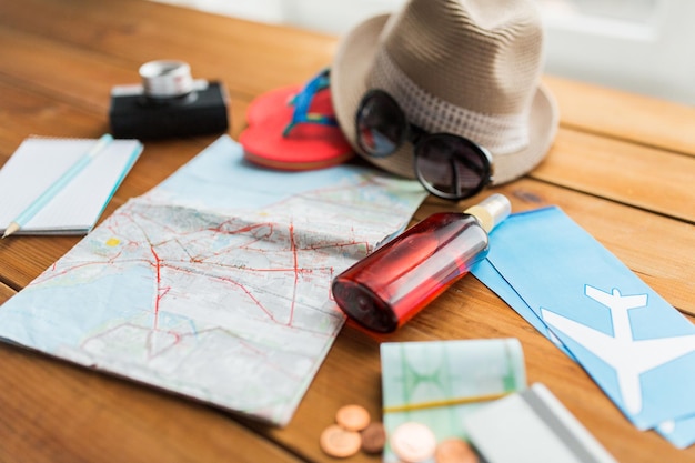 summer vacation, tourism and objects concept - close up of travel map, airplane tickets, money and personal accessories