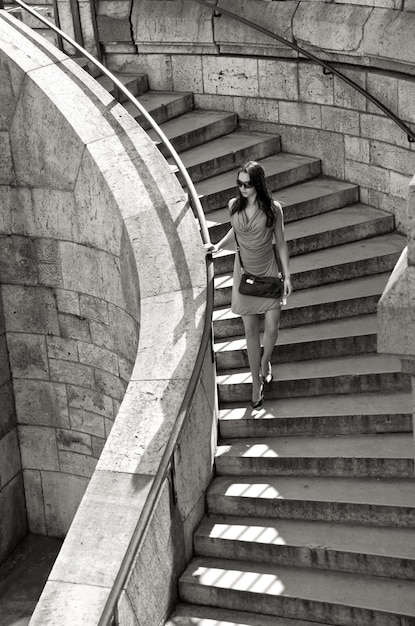 summer, vacation, travel, fashion and people concept - woman in sunglasses and dress walking down stairs with handbag