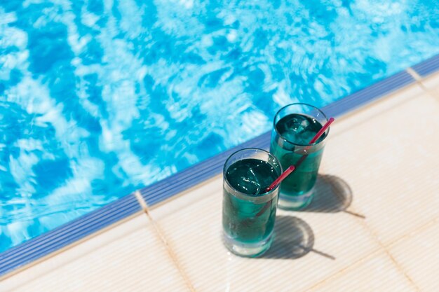 Summer vacation with soft drinks two blue cocktails with ice near the swimming pool in sunny day