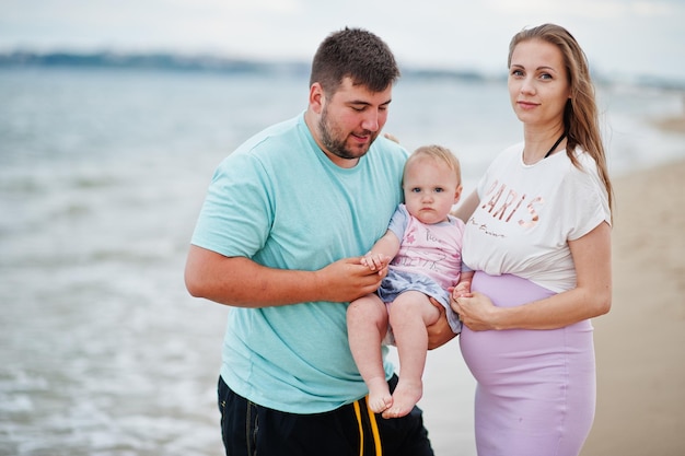 Summer vacations Parents and people outdoor activity with children Happy family holidays Father pregnant mother baby daughter on sea sand beach