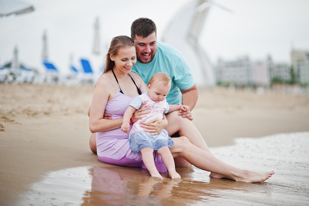 Summer vacations Parents and people outdoor activity with children Happy family holidays Father pregnant mother baby daughter on sea sand beach