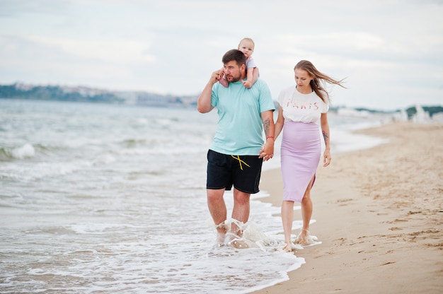 Summer vacations. Parents and people outdoor activity with children. Happy family holidays. Father, pregnant mother, baby daughter on sea sand beach.