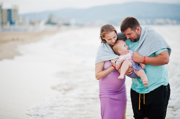 Summer vacations. Parents and people outdoor activity with children. Happy family holidays. Father, pregnant mother, baby daughter on sea sand beach.