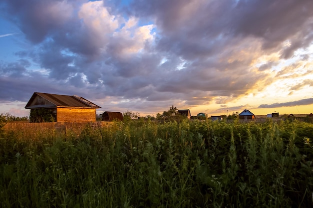 Summer village landscape at sunset with an old wooden house