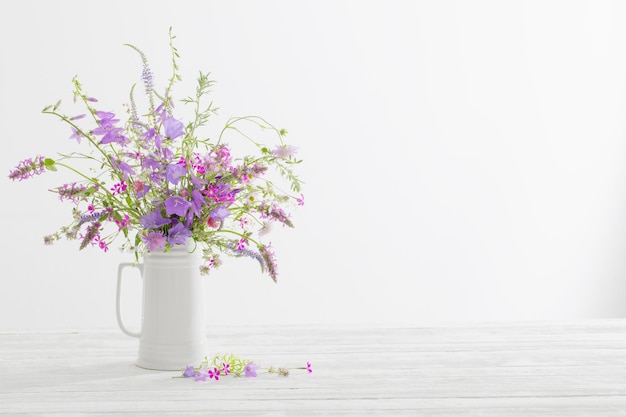 Summer wild flowers in white jug on white background