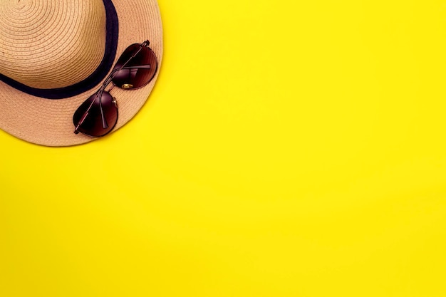 Summer yellow background with hat and sunglasses Flat layout with copy space