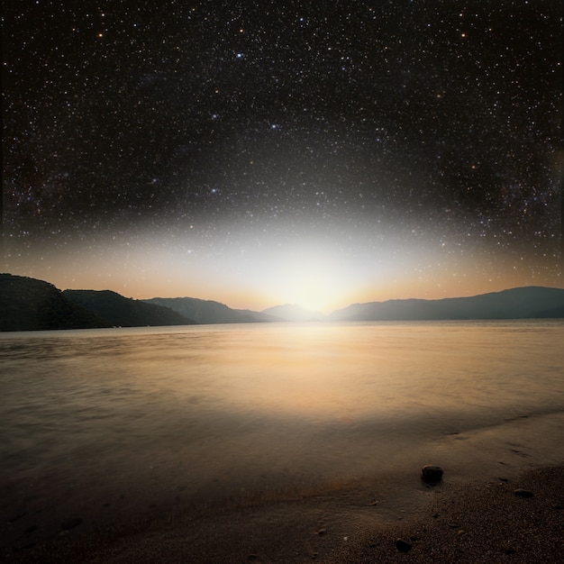 Sun on a background star sky reflected in the sea. Elements of this image furnished by NASA