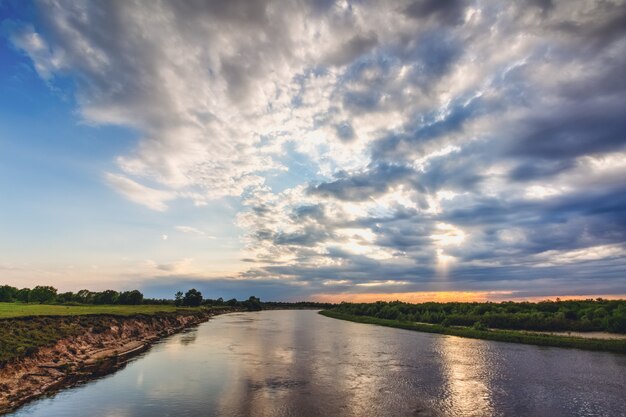 The sun in the clouds above the river