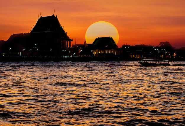 Sun down behind temple next river in Bangkok Thailand