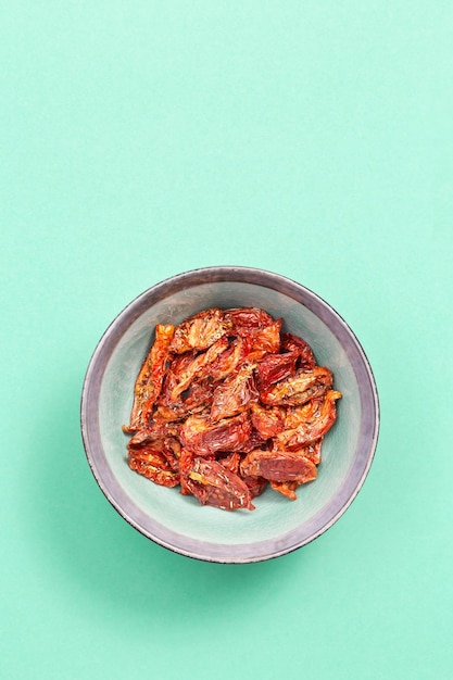 Sun dried tomatoes slices with Italian herbs and spices on blue colored background Homemade