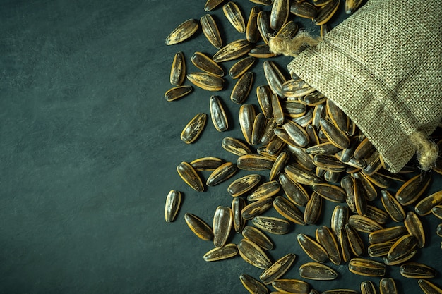 Sun flower seeds in small burlap bag on black cement floor