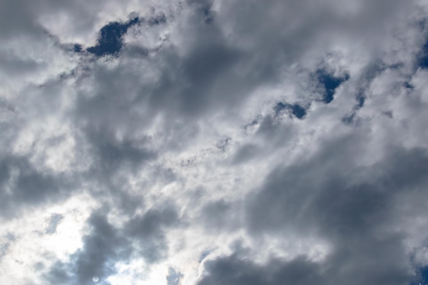 The sun hidden behind white clouds at noon The moon is visible