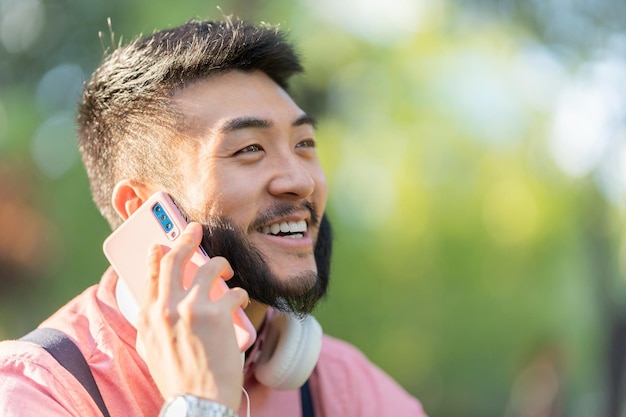 Sun illuminating an asian man talking to the mobile outdoors