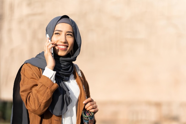 Sun illuminating a muslim woman talking to the mobile outdoors