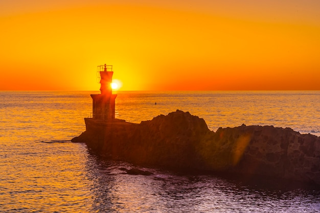 Photo the sun behind the lighthouse at sunset in the town of pasajes san juan. gipuzkoa, basque country