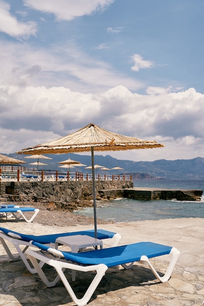 Sun loungers with a table stand under a beach umbrella