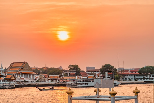 Sun Setting in Bangkok's Chao Phraya river with Buddishm temple with dramatic sky