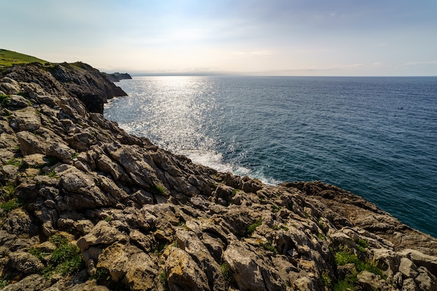 Sun setting on the sea horizon with stone cliffs