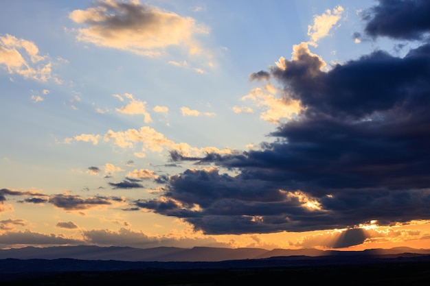 Sun shining through dark clouds in evening