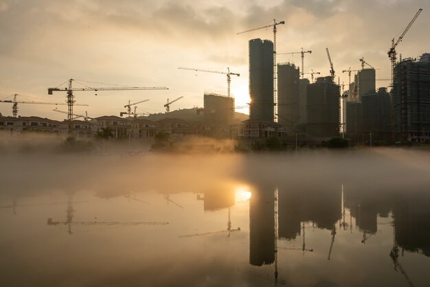 The sun shone on the construction site of the foggy River, which reflected the tall buildings