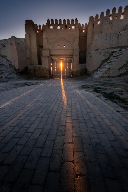 Sunbeams break through old city gates in ancient fortress wall at sunset Bukhara Uzbekistan