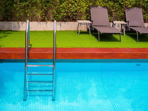 Sunbeds on green glass on outdoor swimming pool in the garden