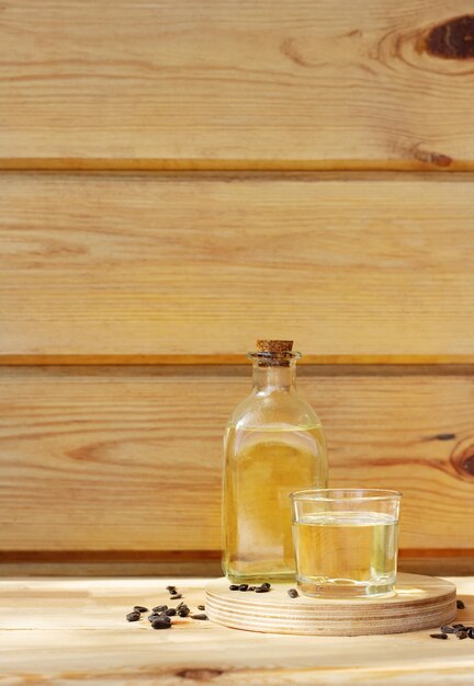 Sunflower oil in a bottle glass with seeds on wooden background