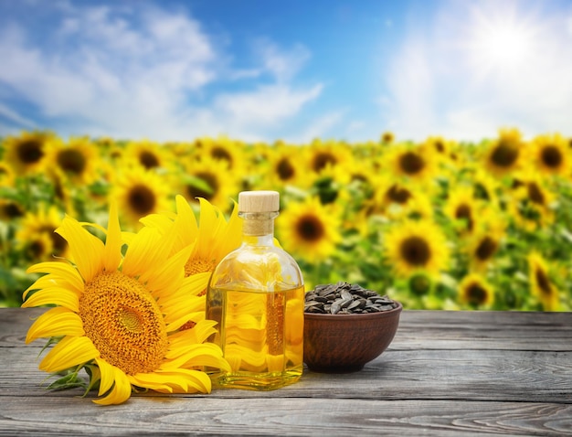 Sunflower oil with seeds and sunflower flower on wooden table