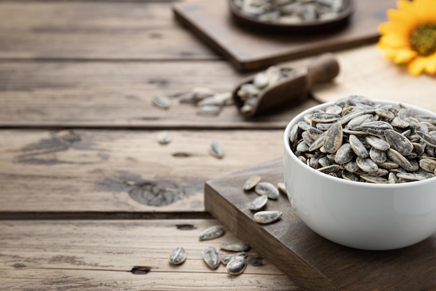 Sunflower seeds with sunflower on dark rustic base with copy space Selective focus