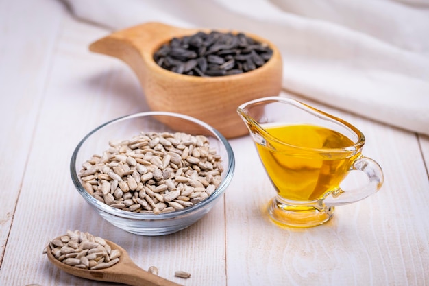 Sunflower vegetable oil in a glass vessel and sunflower seeds on a wooden background