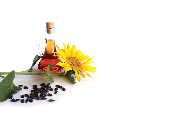 Sunflower with green leaves, black seeds, a bottle of vegetable sunflower oil on a white background.