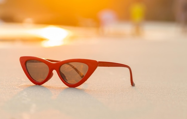 sunglasses on sand beautiful summer beach and golden light of sunset